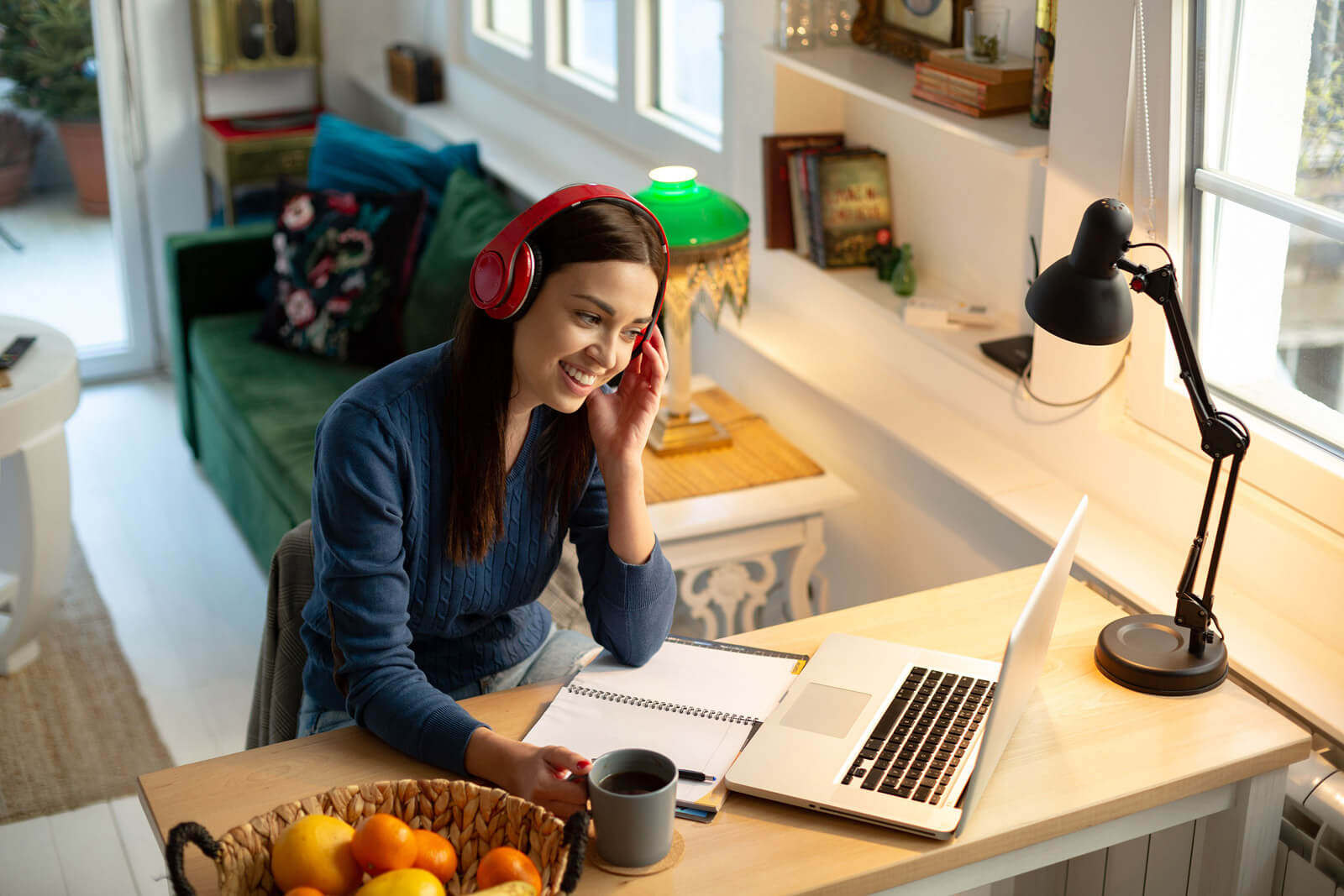 Woman wearing red headphones on laptop and notepad